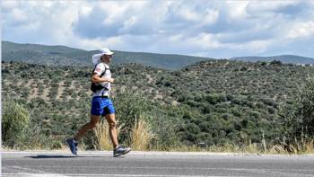 Ένας άντρας τρέχει στον δρόμο και έχει θέα πράσινους λόφους και δέντρα